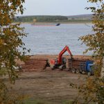 a crane is working on a pile of logs