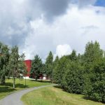 a red building sitting on the side of a lush green field